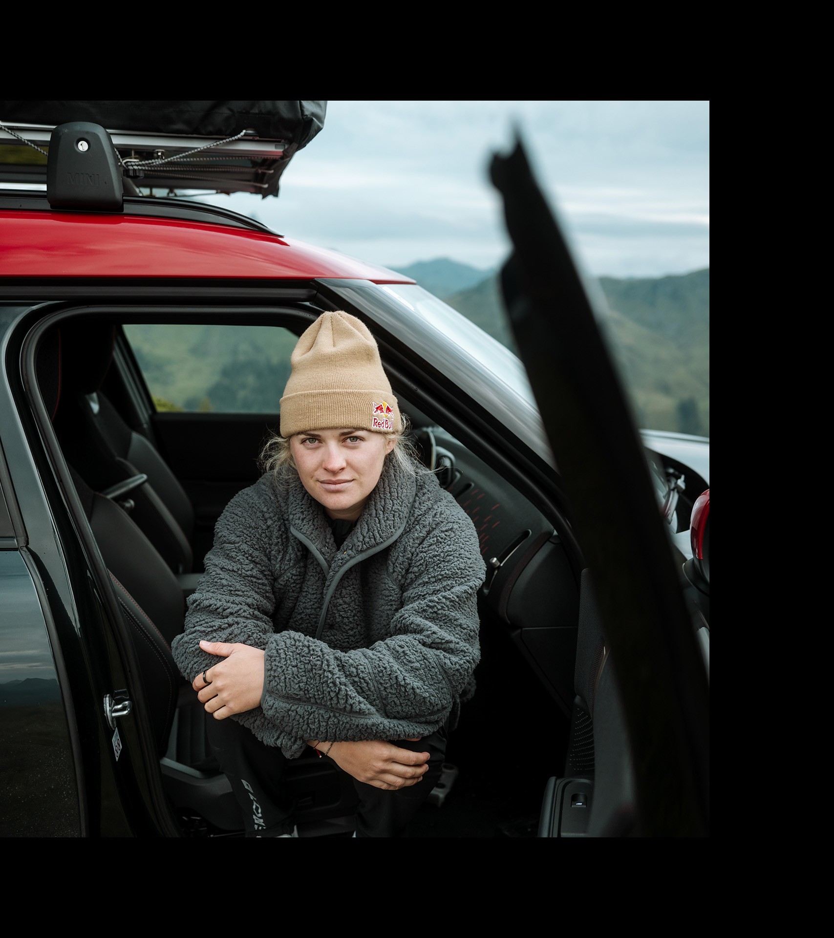 Wearing a grey fleece jumper and beige beanie, Vali Höll poses for a photo from the open passenger side of the new MINI John Cooper Works Countryman.